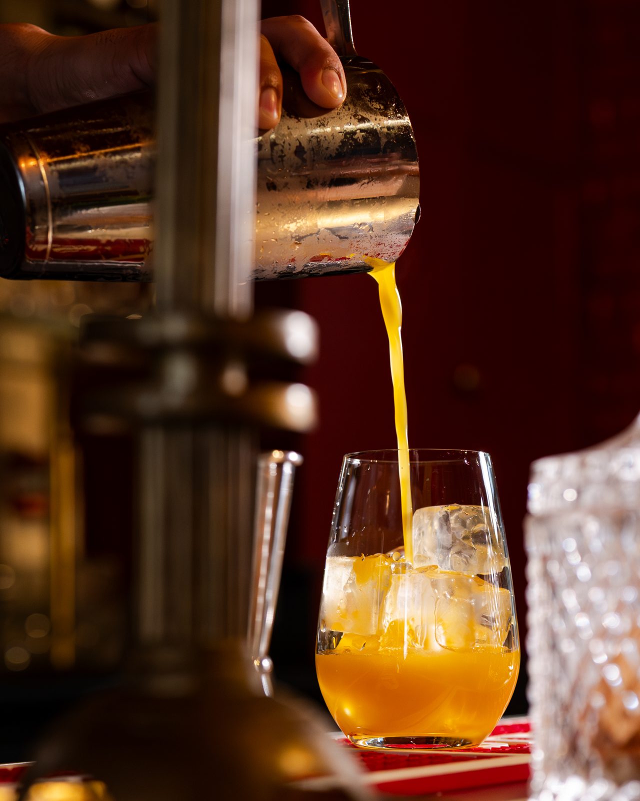 Cocktail ambré versé au shaker devant les tireuses à bière d'un pub parisien