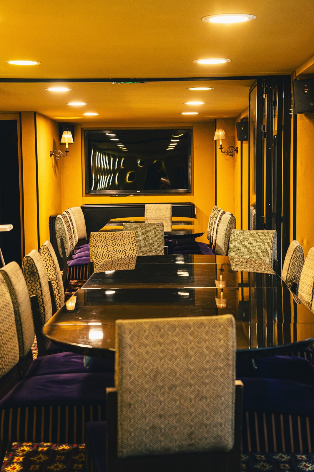 Salon privatisable aux murs jaunes avec grande table de réunion et chaises violettes