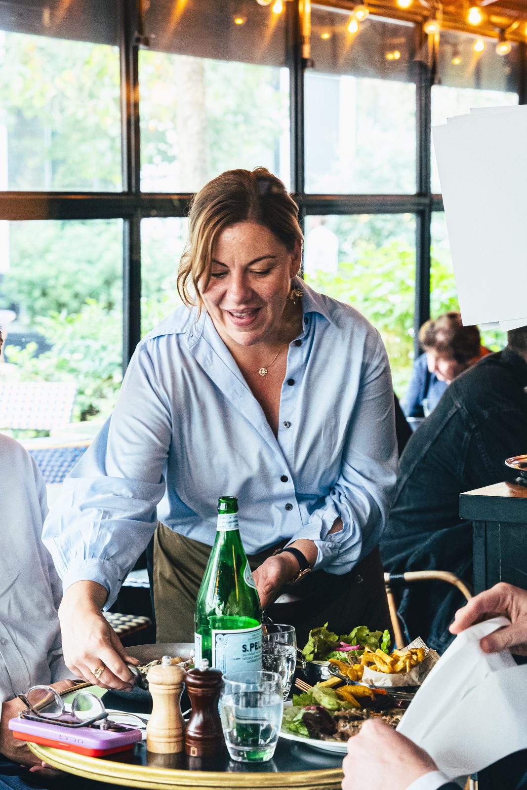 Serveuse apportant les plats à une table près d'une baie vitrée