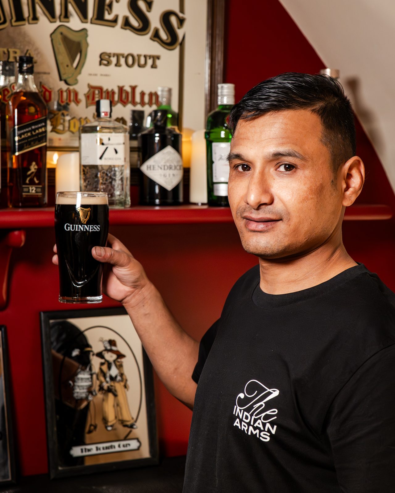 Le chef de The Indian Arms tenant une pinte de stout devant le comptoir