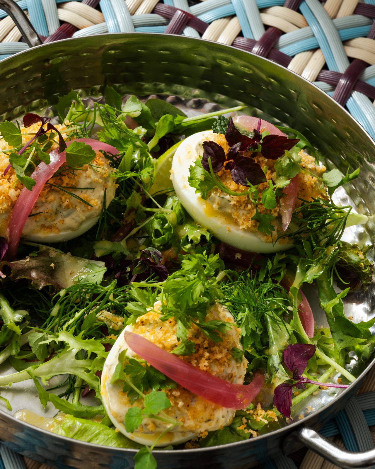 Salade d'œufs mimosa et herbes fraîches servie dans un plat en métal, vue de près