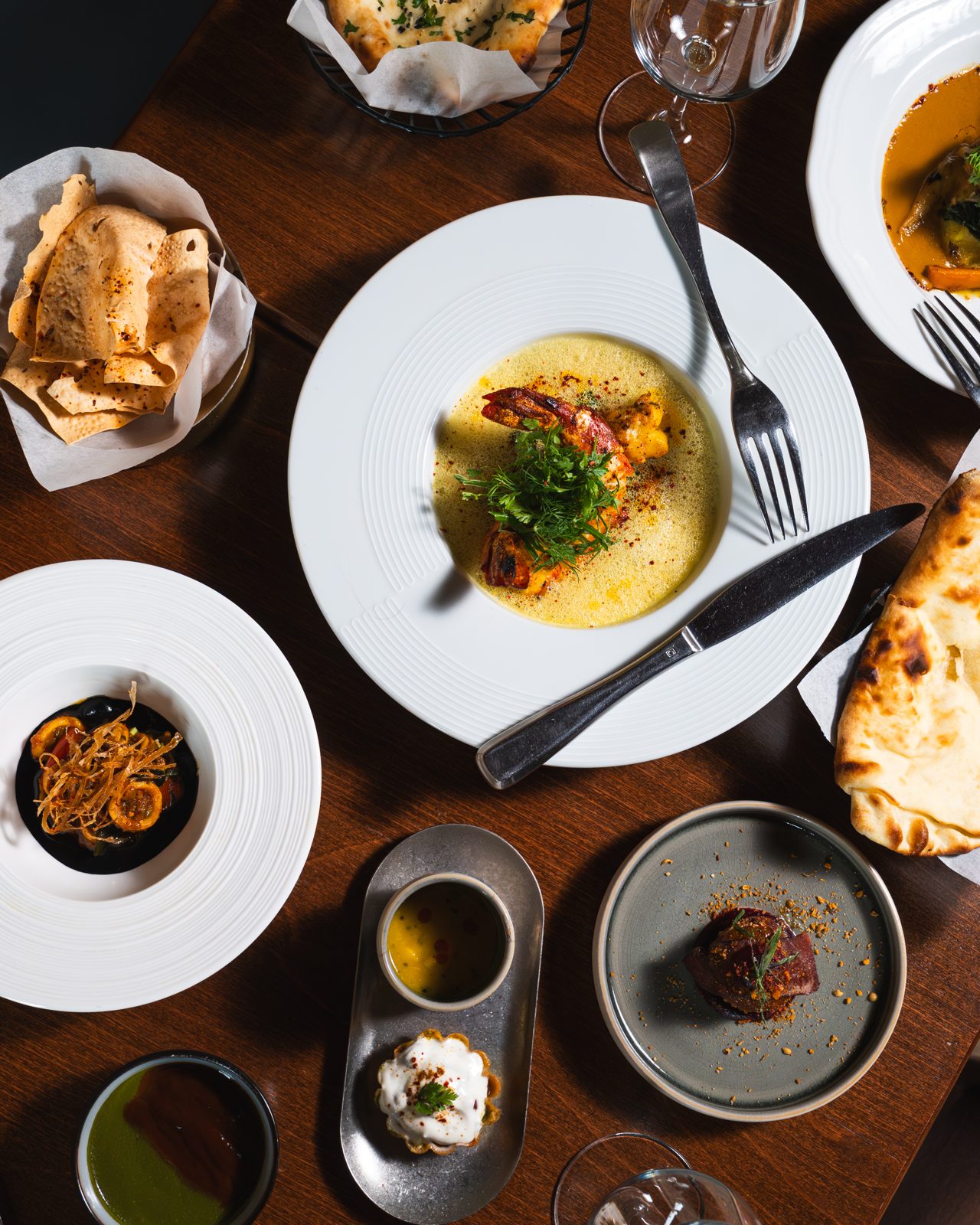 Table vue du dessus avec plusieurs plats indiens, naans et sauces chez Sharma Ji, Paris 15e