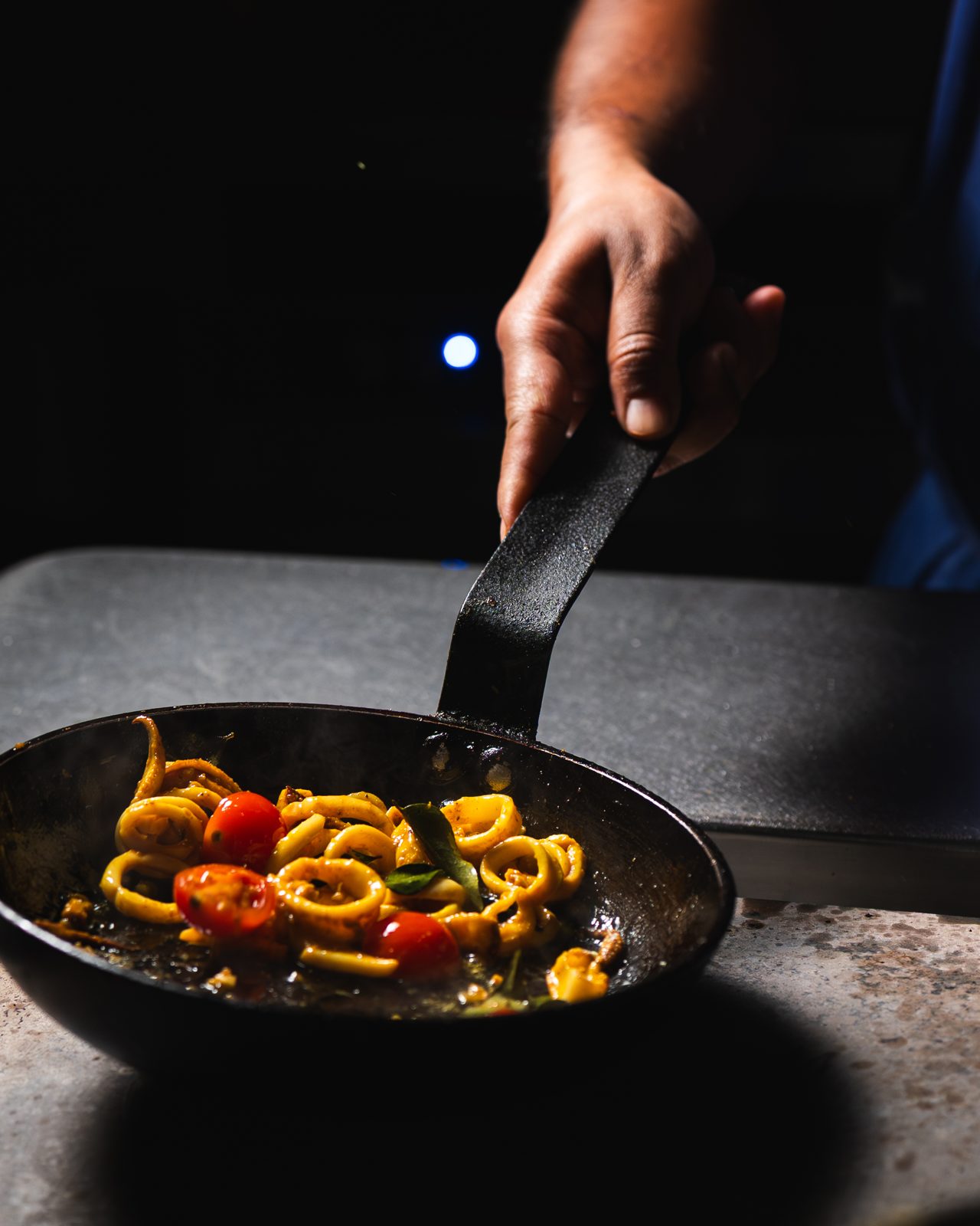 Cuisinier faisant sauter des légumes dans une poêle en cuisine chez Sharma Ji, Paris 15e