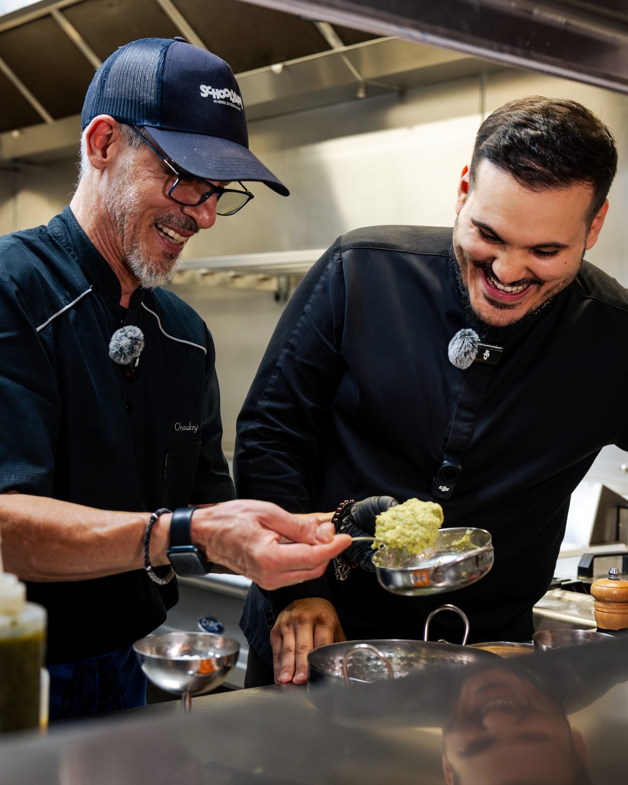 Deux chefs souriants dressant une assiette en cuisine pendant un tournage