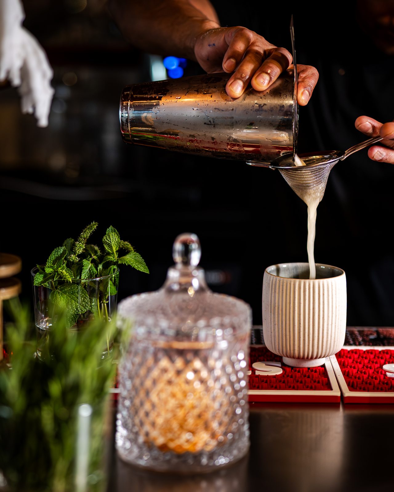 Barman versant un cocktail à travers une passoire au bar de The Indian Arms